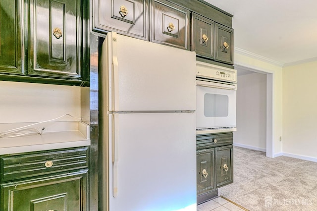 kitchen featuring light colored carpet, white appliances, baseboards, ornamental molding, and green cabinets