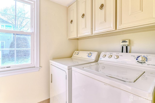 clothes washing area featuring separate washer and dryer and cabinet space