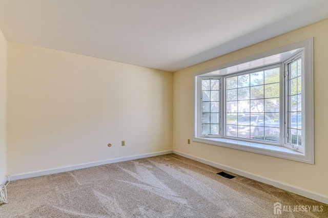 spare room featuring visible vents, carpet floors, and a wealth of natural light