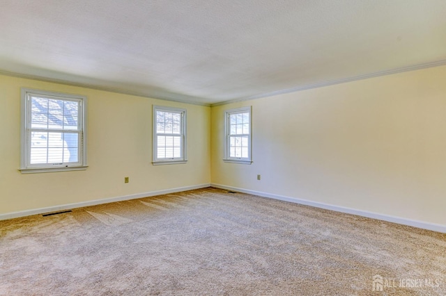 carpeted empty room with crown molding, baseboards, and visible vents