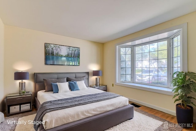 bedroom featuring baseboards, wood finished floors, visible vents, and multiple windows