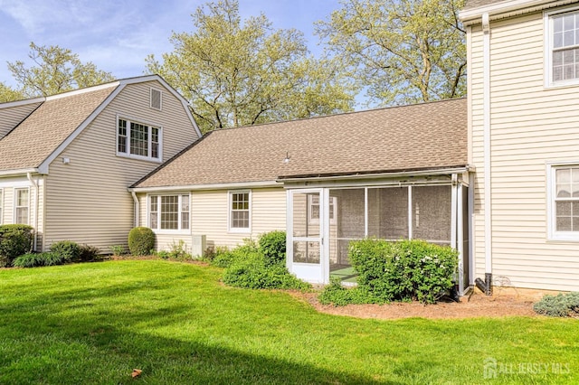 rear view of house with a yard, a shingled roof, and a sunroom
