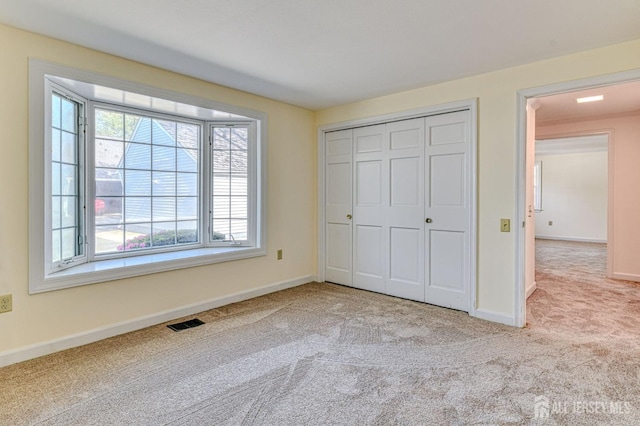 unfurnished bedroom with carpet floors, baseboards, and multiple windows