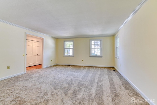carpeted empty room featuring crown molding and baseboards