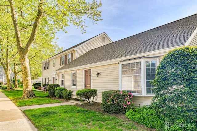 colonial house with a shingled roof and a front yard