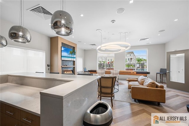 702 Station Rd, Dunellen, NJ 08812 - kitchen featuring open floor plan, decorative light fixtures, dark brown cabinets, a warm lit fireplace, and recessed lighting