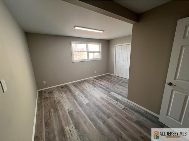 unfurnished bedroom featuring wood finished floors, a closet, and baseboards