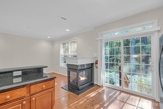 97 Osprey Dr, Old Bridge, NJ 08857 - kitchen with light wood-style floors, brown cabinetry, dark stone countertops, a multi sided fireplace, and crown molding