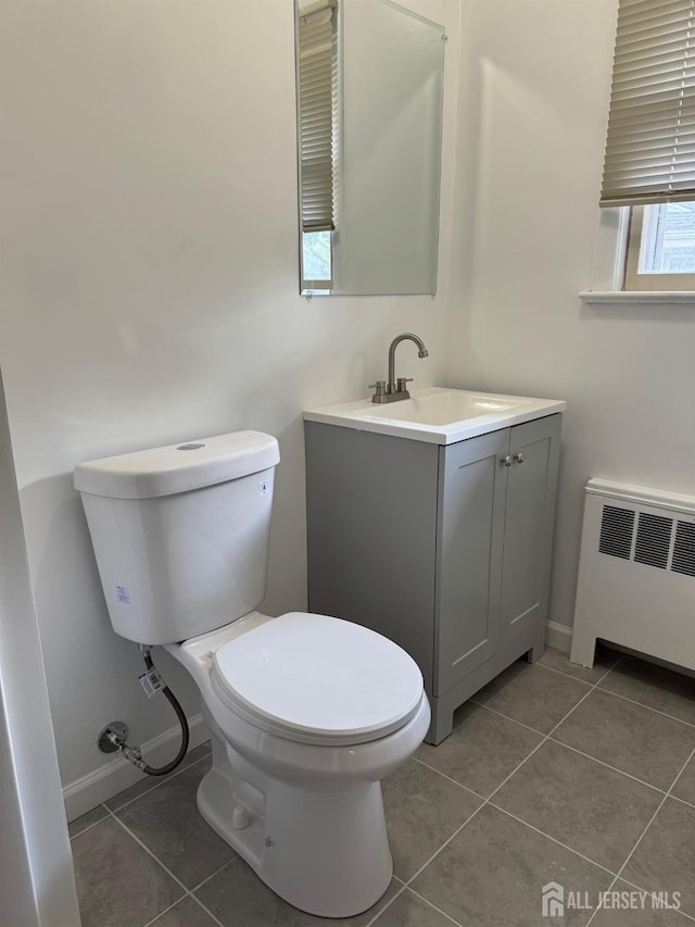 bathroom with tile patterned flooring, radiator, vanity, and toilet