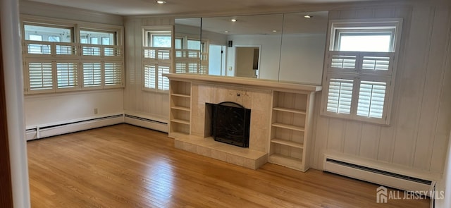 unfurnished living room featuring a baseboard radiator, a tile fireplace, and light hardwood / wood-style flooring