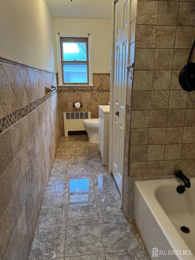 bathroom featuring tile walls, vanity, radiator heating unit, and toilet