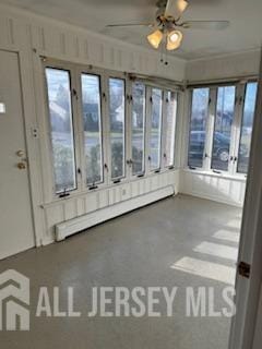 unfurnished sunroom featuring baseboard heating and ceiling fan