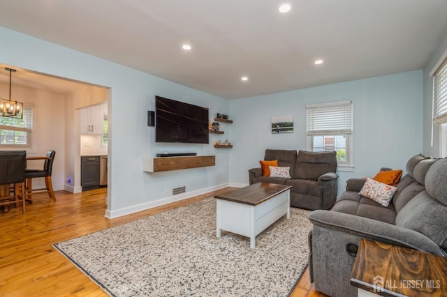 living room with an inviting chandelier and light hardwood / wood-style flooring