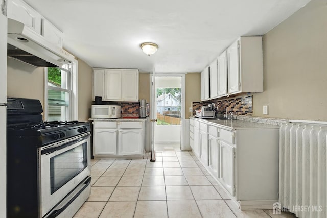 309 1st St, Keyport, NJ 07735 - kitchen featuring stainless steel gas stove, radiator, white microwave, under cabinet range hood, and tasteful backsplash