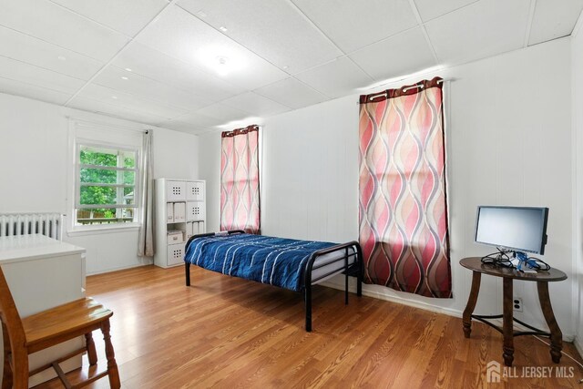 309 1st St, Keyport, NJ 07735 - bedroom featuring radiator heating unit, light wood-style flooring, and a drop ceiling