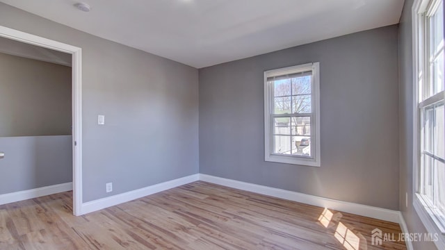 spare room featuring baseboards and light wood-style floors