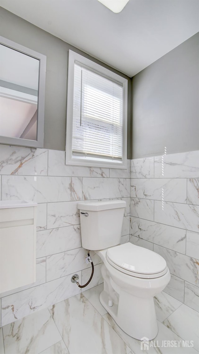 bathroom featuring toilet, tile walls, and wainscoting