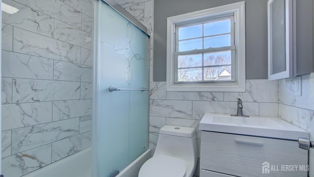 bathroom with vanity, tile walls, toilet, and shower / bath combination