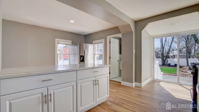 kitchen featuring stainless steel fridge with ice dispenser, baseboards, light wood-style floors, white cabinetry, and plenty of natural light