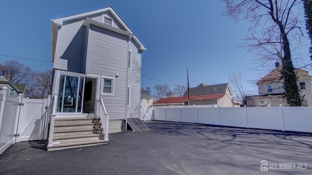 back of property featuring entry steps, fence, and a gate