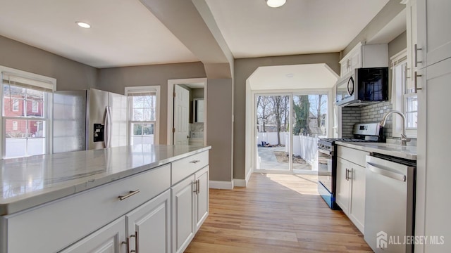 kitchen with a wealth of natural light, white cabinets, and appliances with stainless steel finishes