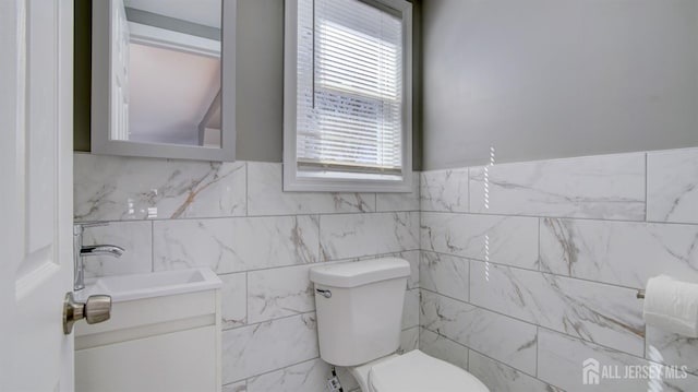 bathroom with vanity, toilet, and a wainscoted wall