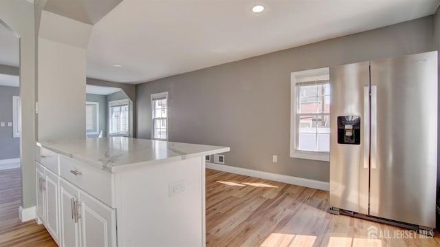 kitchen with stainless steel fridge with ice dispenser, baseboards, light stone counters, light wood-style floors, and white cabinets