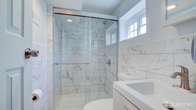 bathroom featuring vanity, toilet, a shower stall, and tile walls