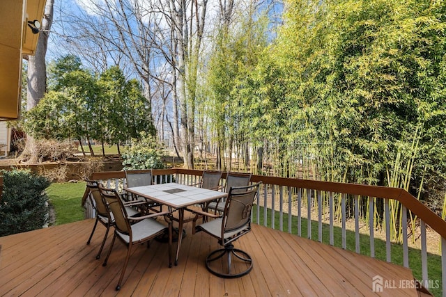 wooden deck with outdoor dining area and a yard
