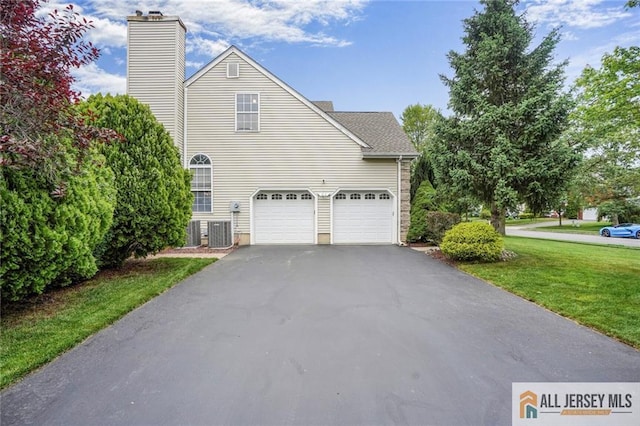 9 Lavender Way E, Brunswick, NJ 08816 - view of side of home featuring asphalt driveway, an attached garage, a yard, and a chimney