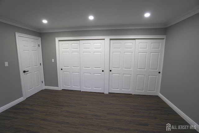 unfurnished bedroom with dark hardwood / wood-style flooring, crown molding, and multiple closets