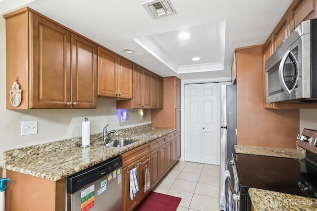 kitchen featuring sink, light tile patterned floors, appliances with stainless steel finishes, a tray ceiling, and light stone countertops