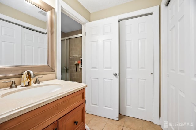 bathroom with vanity, a shower with door, and tile patterned floors