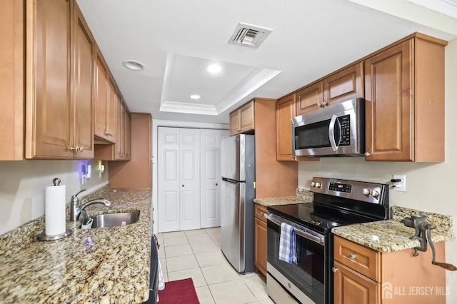 kitchen featuring sink, light tile patterned floors, a tray ceiling, stainless steel appliances, and crown molding