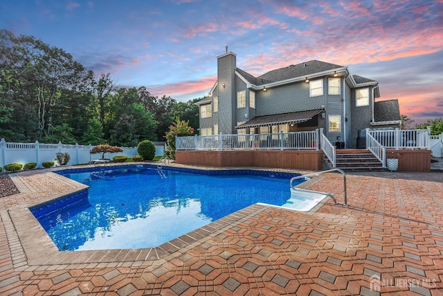 pool at dusk featuring a jacuzzi and a patio