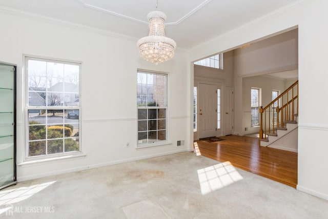 foyer featuring stairway, a notable chandelier, a wealth of natural light, and ornamental molding