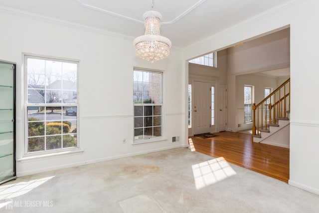 carpeted entryway with a notable chandelier, stairway, baseboards, visible vents, and ornamental molding