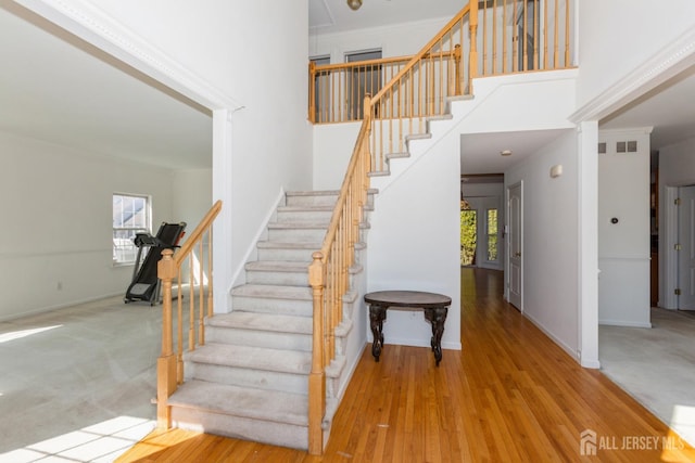 stairs with carpet flooring, a towering ceiling, and baseboards