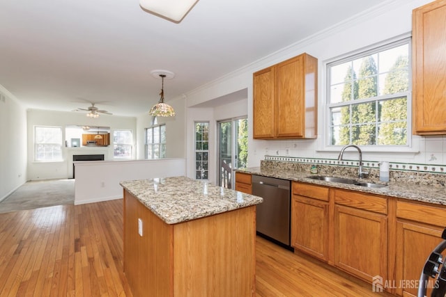 kitchen with light wood-type flooring, a sink, tasteful backsplash, stainless steel dishwasher, and a center island