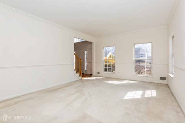 carpeted spare room featuring baseboards, visible vents, crown molding, and stairway