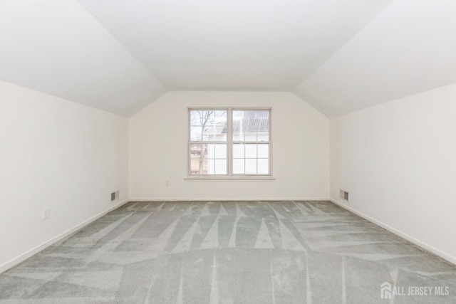 additional living space with vaulted ceiling, carpet flooring, baseboards, and visible vents