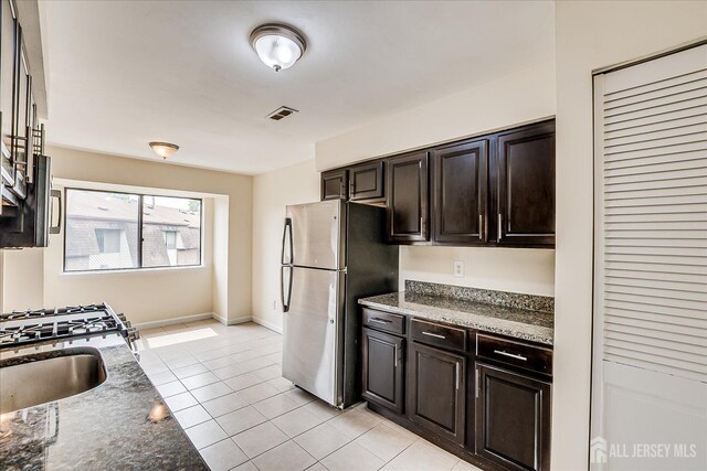 223 Edison Glen Ter, Edison, NJ 08837 - kitchen with freestanding refrigerator, stone countertops, light tile patterned floors, and dark brown cabinetry