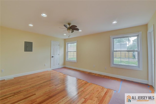 spare room featuring a ceiling fan, light wood-type flooring, recessed lighting, baseboards, and electric panel