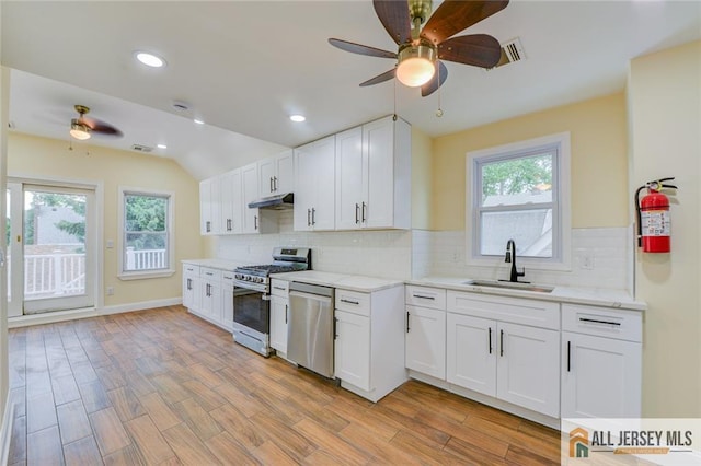 kitchen featuring stainless steel appliances, a ceiling fan, a sink, under cabinet range hood, and white cabinets