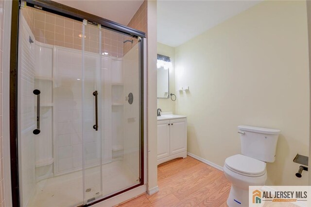 full bathroom with wood finished floors, a shower stall, toilet, and vanity
