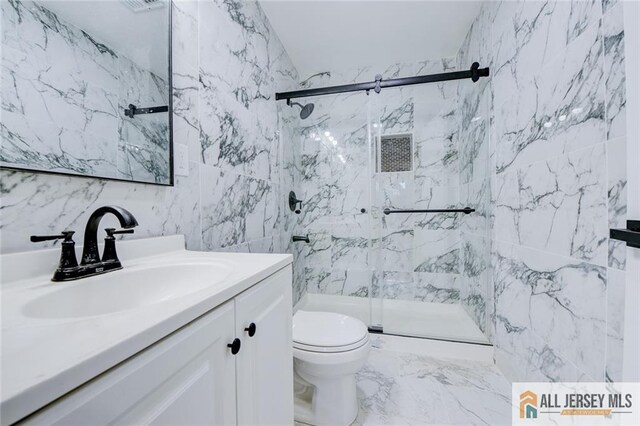 full bath featuring tile walls, a marble finish shower, vanity, toilet, and marble finish flooring