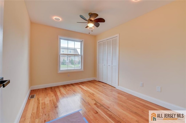 unfurnished bedroom featuring wood finished floors, baseboards, a closet, and a ceiling fan
