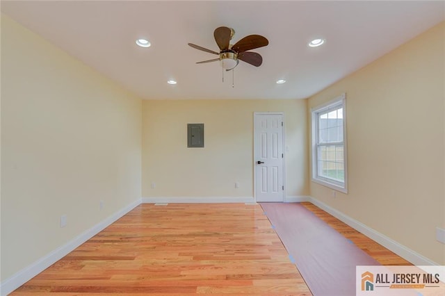 empty room with electric panel, light wood-style flooring, recessed lighting, a ceiling fan, and baseboards
