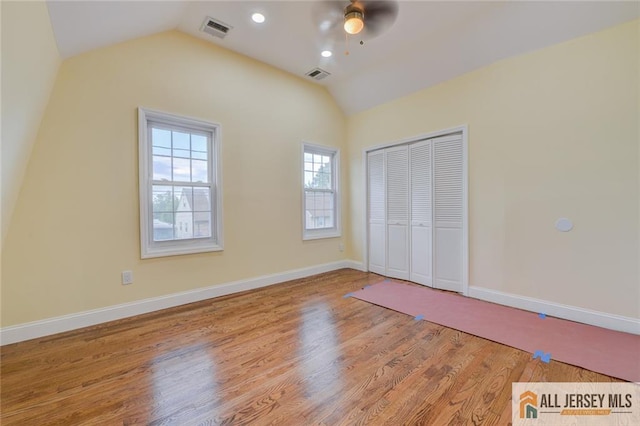 unfurnished bedroom with vaulted ceiling, wood finished floors, a closet, baseboards, and a ceiling fan