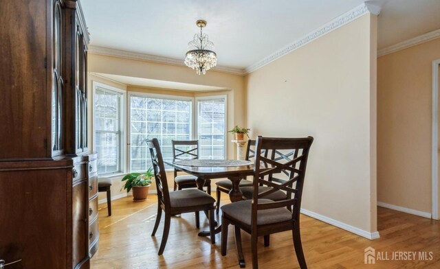 dining space featuring plenty of natural light, baseboards, light wood-style floors, a chandelier, and ornamental molding
